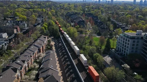 Container freight train running through urban neighborhood with modern apartment Stock Footage 334696927