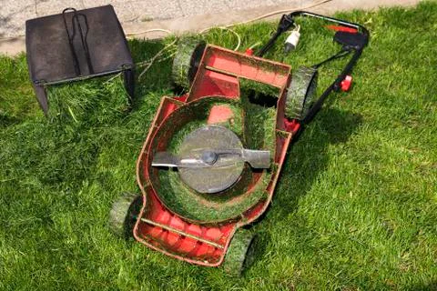 Container full of cutting grass and red mower upside down Stock Photos