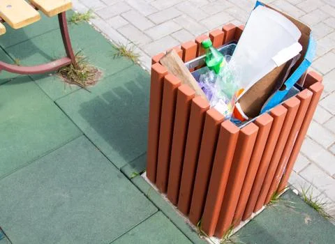 The container is full of garbage with various waste standing on the ground Stock Photos