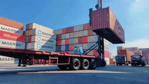 Container-handling machine lifting a Maersk container in a spacious port area Stock Footage 312021669