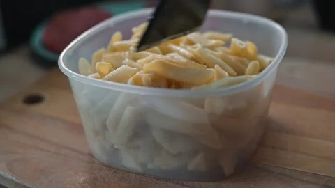 A container holds cooked pasta and a kitchen utensil is used to serve it. This Stock-Footage 338304053