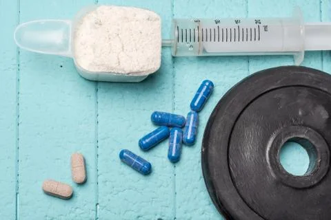 Container of milk whey protein, empty injection and pills. Close-up. Blue Foto stock