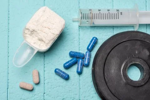 Container of milk whey protein, empty injection and pills. Close-up. Blue Stock Photos