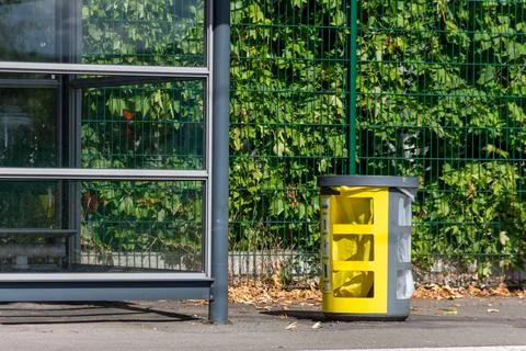 The container near the bus stop is designed for waste disposal Stock Photos