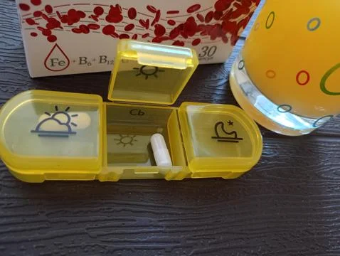 A container with an open compartment and an iron supplement capsule Stock Photos