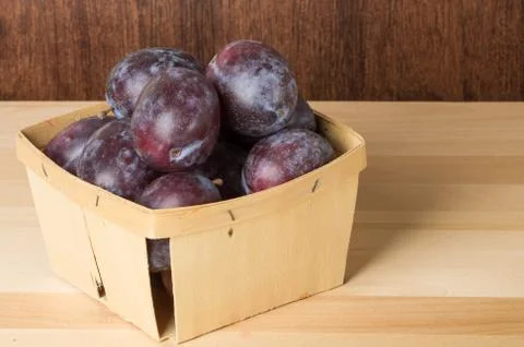 Container of prune plums on table Stock Photos
