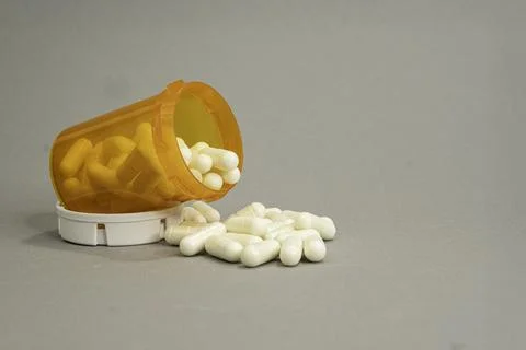 Container of RX capsules on its side with some spilled out. Stock Photos