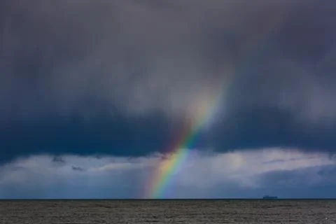 Container ship and Rainbow over water with dark storm clouds on the Strait .. Stock Photos