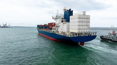 Container Ship Departing Harbor Guided By Tugboat In Thailand 库存照片