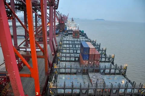 Container ship docking at large industrial port with cranes Stock Photos