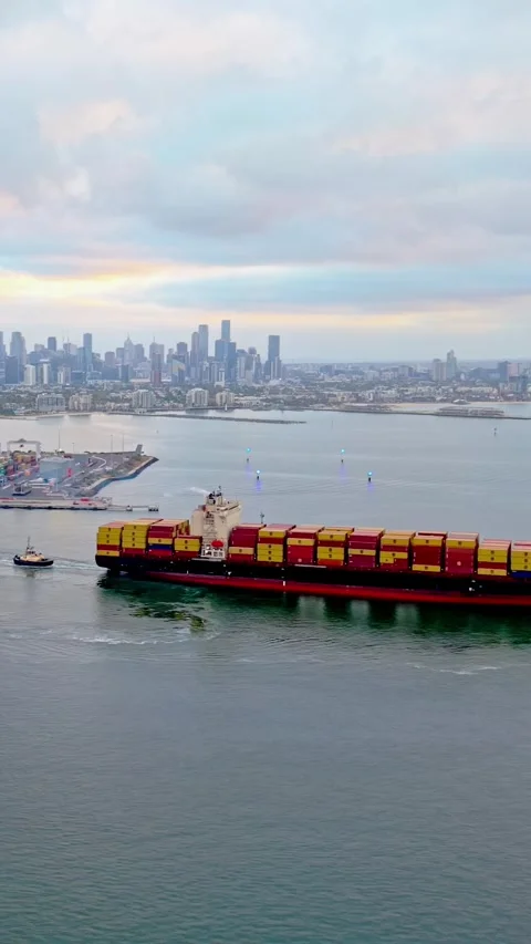 Container ship entering Port of Melbourne with city skyline Stockbeeldmateriaal 332778501