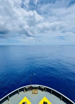Container Ship Foredeck Approaching Open Tropical Waters Under Cloudy Sky Stock Photos