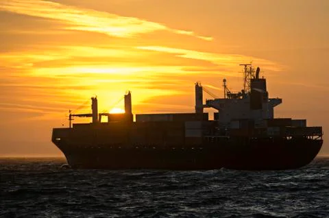 Container ship in front of sunset Stock Photos