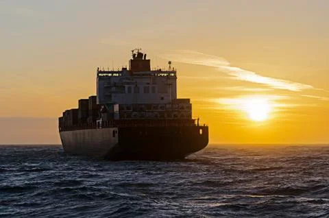 Container ship heading towards sunset Stock Photos