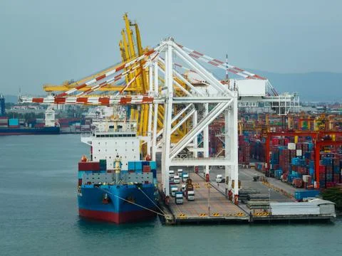 Container Ship Loading Cargo At Industrial Seaport During Daylight Aerial Vie 库存照片