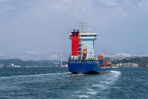 Container ship navigates the waters of the Bosphorus on a clear day amid the Stock Photos