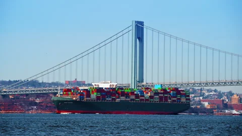 Container ship passing large bridge pylon at sunset. Green cargo vessel moving Stock Footage 328968172