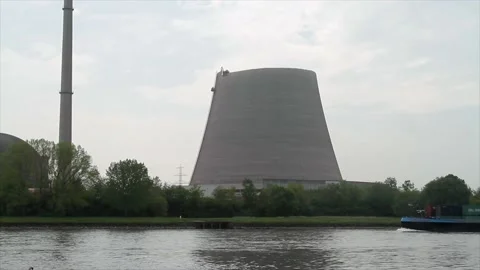A container ship on the river Rhine passing a partly broken down cooling tower Stock Footage 170323848