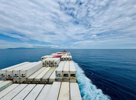 Container Ship Sailing Across the Open Ocean Under Dramatic Cloudy Sky Foto stock