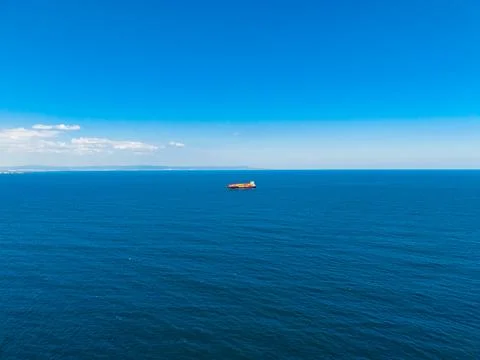 Container ship sailing on calm waters under clear blue sky in the distance .. Фото