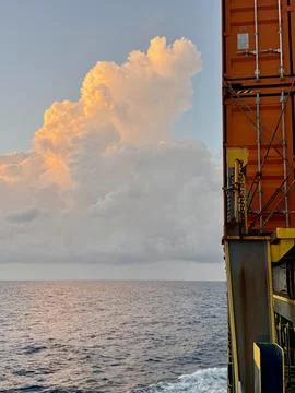 Container Ship Side With Dramatic Cloud Formation Over Calm Ocean Stock Photos