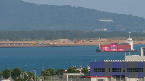 Container ship transporting cargo on sea with hills in background Singapore Stockbeeldmateriaal 342346746