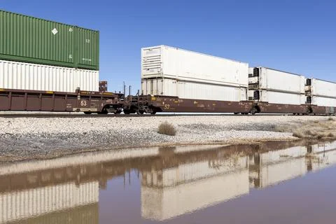 Container stack train reflected in puddle Foto stock