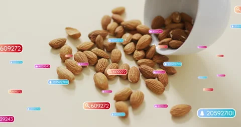 Container tilting releasing almonds onto tabletop while digital widgets floating Stock Footage 309680471