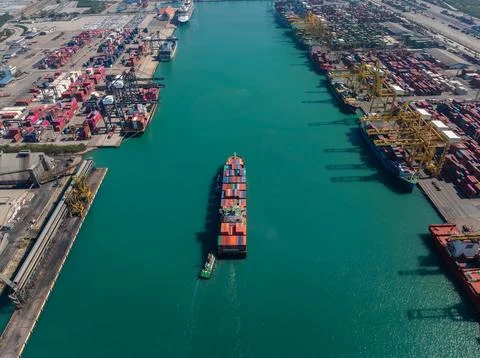 Container Vessel Navigating Through Busy Industrial Port Terminal In Thaila.. Stock Photos