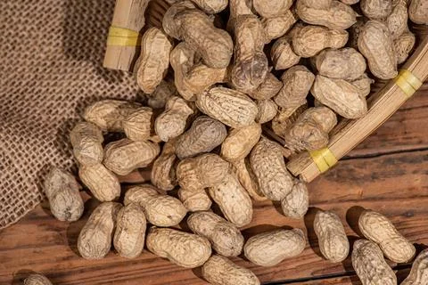 The container on the wood grain table is full of peanuts Foto stock