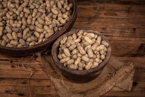 The container on the wood grain table is full of peanuts Foto stock