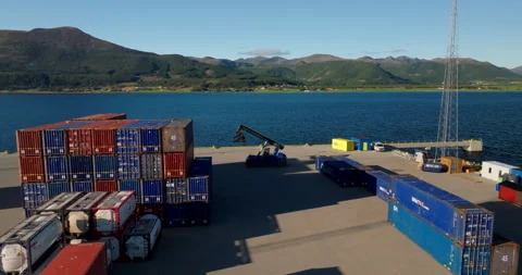 Container yard by waterfront with scenic mountain backdrop, aerial view Stock Footage 333426508