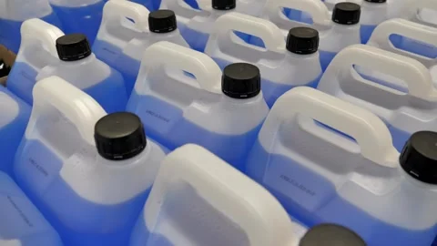 Containers filled with blue liquid lined up for storage at a facility Stock Footage 297398465