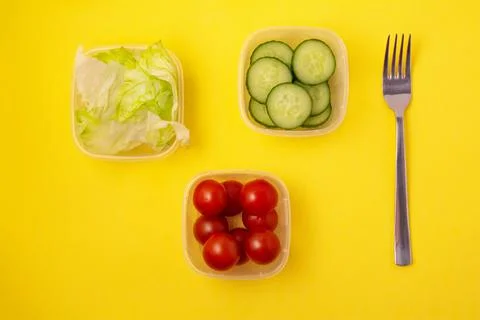 Containers with fresh vegetables on a yellow background Stock Photos