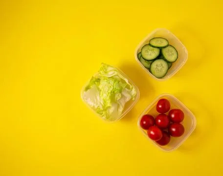 Containers with fresh vegetables on a yellow background Stock Photos