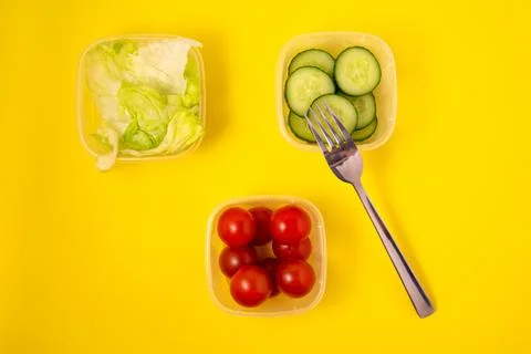 Containers with fresh vegetables on a yellow background Stock Photos