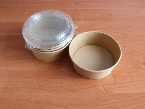 Containers made of paper and plastic stacked on a wooden table in a kitchen or Stock Photos