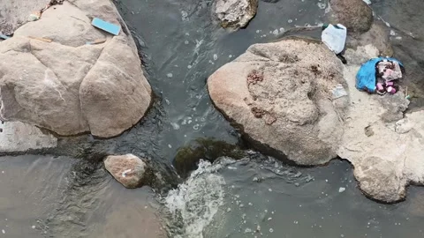 Contaminated Stream Water Flowing Through Rocks With Trash Видео 330325844