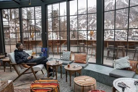 Contemplating man having coffee while looking at mountains from window in resort Stock Photos