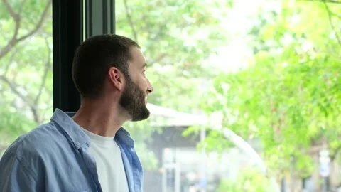 Contemplative bearded man looking out a window and smiling Stock Footage 335588076