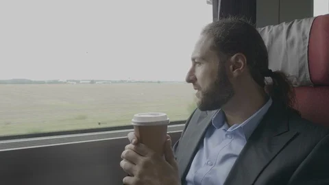 Contemplative businessman commuter on train drinking coffee and admiring the  Stock Footage 102587096