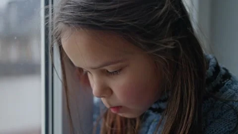 A Contemplative Child Deeply Gazing Out of a Window While Wearing a Cozy Sweater Stock Footage 304800149