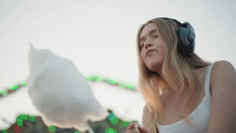 Contemplative DJ holding cotton candy during lively carnival evening, Intimate Stock Footage 333655273