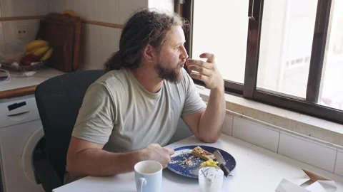 Contemplative man eating breakfast alone at home Stock Footage 319749533