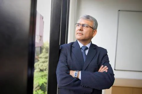 Contemplative mature businessman looking through window at workplace Stock Photos
