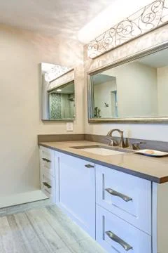 Contemporary bathroom design boasts white bathroom cabinet with taupe Quartz  Stock Photos