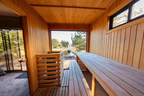 Contemporary cedar sauna interior with panoramic window near coastal path Stock Photos