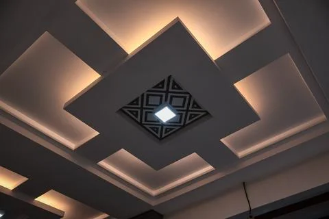 Contemporary ceiling design featuring geometric patterns and recessed light.. Stock Photos
