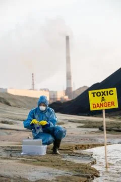 Contemporary ecologist putting flask with sample of toxic soil or water in flask Fotos de archivo