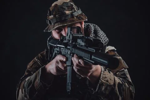 Contemporary fighter in camouflage costume aims a rifle Фото